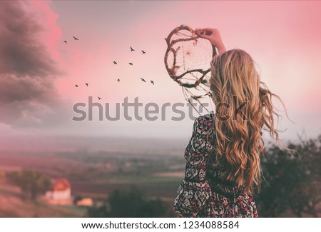 Bohemian girl with long blonde hair standing and holding dreamcatcher.Freedom