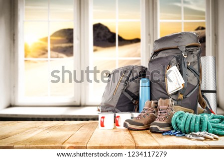 Winter photo of backpack on table and background of winter window with mountains landscape. Free space for your decoration. 