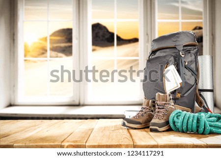 Winter photo of backpack on table and background of winter window with mountains landscape. Free space for your decoration. 