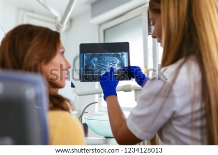 Female dentist explaining x-ray image to a patient at dentist's office