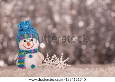 Smiling snowman and snowflakes on a gray background with bokeh effect