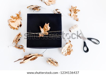 Luxury New Year gift with gold leaves decoration. Christmas background with gift box. Presents for Christmastime celebration.