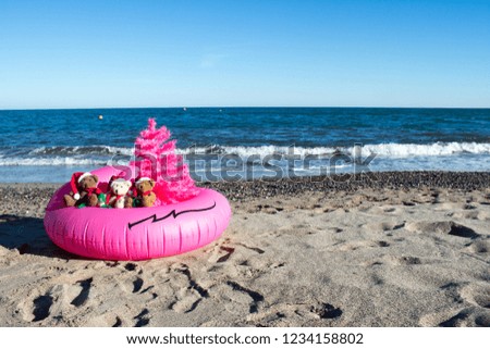 Christmas Holiday Is Coming. Santa Bears in a pink buoy with a pink christmas tree by the sea. Merry Christmas Postcard Design with copy space. Unusual Christmas Design Concept.