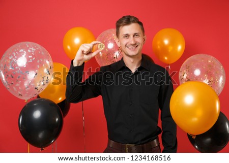 Joyful young man in classic shirt hold bitcoin metal coin of golden color future currency on red background air balloon. International Women's Day Happy New Year birthday mockup holiday party concept
