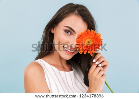Image of amazing beautiful young woman isolated over blue background wall holding flower.