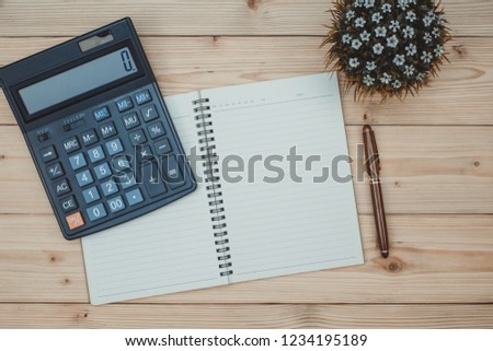 Office supplies or office work essential tools items on wooden desk in workplace, pen with notebook and calculator with copy space, top view