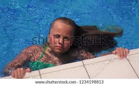 Pretty little girl with long blonde hair swiimming in the pool in sunny day
