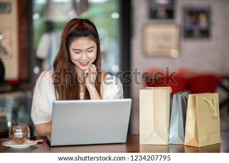Beautiful Attractive Asian woman using computer laptop shopping online with shopping bags inside feeling so enjoy and happiness,Shopping online Concept