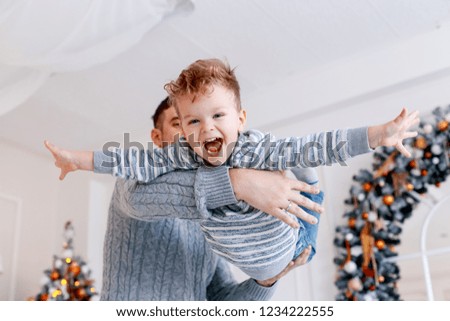 A daddy with his two sons twins in front of the christmas tree  with candles and gifts hugging and having fun. New year's eve. Cozy holiday at the fir-tree. love, happiness and big family concept