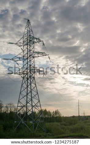 A high column high-voltage power lines against the evening sky.