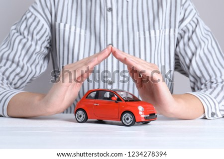 Insurance agent covering toy car on table, closeup