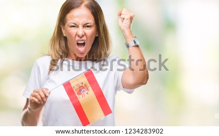 Middle age hispanic woman holding flag of Spain over isolated background annoyed and frustrated shouting with anger, crazy and yelling with raised hand, anger concept