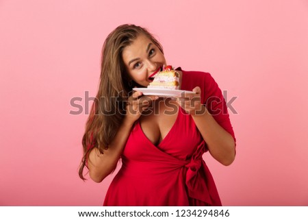 Image of a happy young woman isolated over pink wall background holding cake.