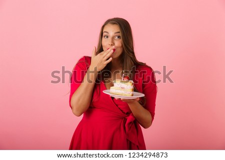 Image of a happy young woman isolated over pink wall background holding cake.