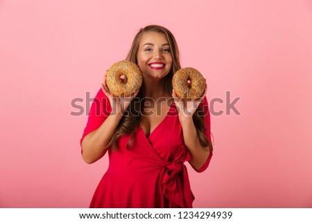 Image of a happy young woman isolated over pink wall background holding donuts.