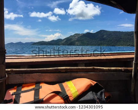 View from the boat, see the island and the sea. Side view of a longtail boat in the sea overlooking the island.