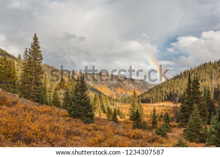 A valley near Aspen, Colorado with yellow aspen trees and a rainbow.