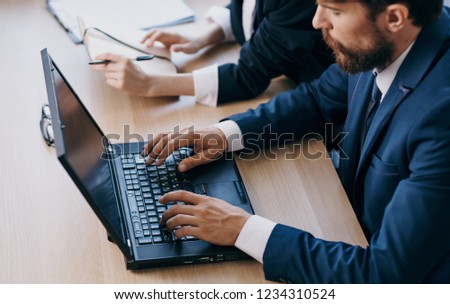 business man behind a laptop next to a woman                    