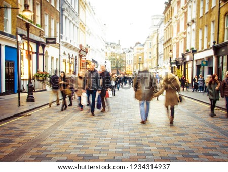 Shoppers walking on busy high street- motion blurred and defocused Royalty-Free Stock Photo #1234314937