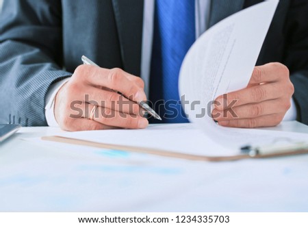 Businessman in dark suit sitting at office desk signing a contra