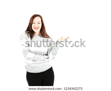 Beautiful young woman wearing a christmas jumper while doing a hand gesture to one side against a white background