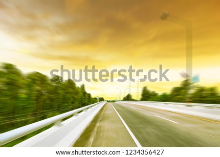 Beauty empty highway road with lamp post and tree on golden sunset motion blur background