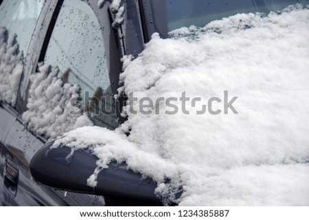Wing mirror of car covered up with snow in winter time, close up. Empty window for your message. Image has copy space for text
