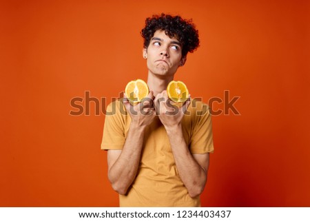 the guy is holding slices of orange                  