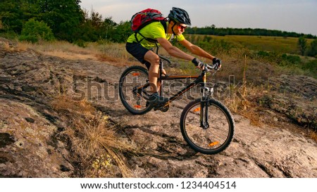 Cyclist Riding the Bike on the Rocky Trail at Sunset. Extreme Sport and Enduro Biking Concept.