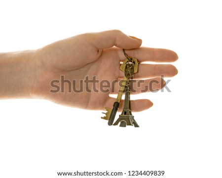 Hand holding a key with Eiffel Tower keychain. White background.