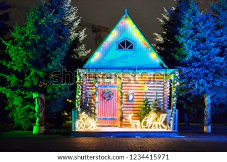 Suit and cozy house near forest decorated for the winter holidays. Colored lights around the front of the building. New year and mery christmas. Royalty-Free Stock Photo #1234415971
