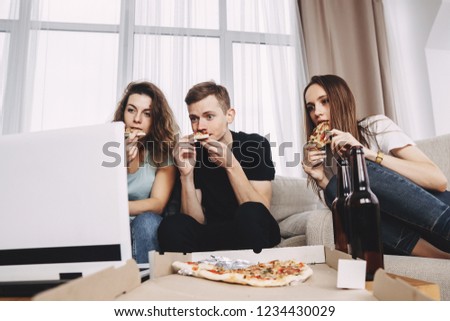 food delivery, home party, conversation and leisure, social media. company of friends engrossed in watching fascinating picture on laptop and eating pizza