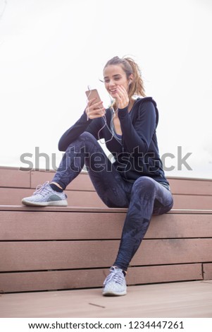 Young  fit sporty woman resting and listen music on mobile phone after  training  outdoor in urban environment