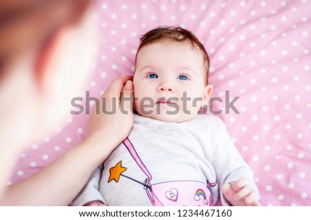 Cute adorable Caucasian baby girl looking at her caring mother. Happy childhood concept image. Mother caressing her beloved tiny newborn daughter image. 