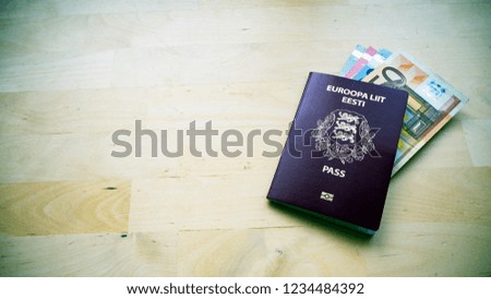 Passport on the wooden background. Passports of Estonia and European Union (EU)  Top view. Copy space for design. Euro banknotes. Toned picture