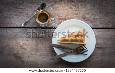 Black coffee in clear glass And almond cake in blue plate All on a wooden table.