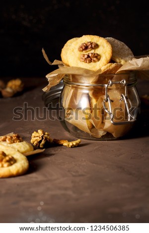Healthy vegan homemade handmade cookies with walnuts in glass jar on brown background, closeup, blank space