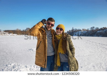 A loving couple of young people are laughing at the camera. Winter sunny day.