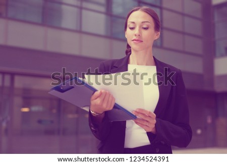 Businesswoman is examining documents before signing outdoors.