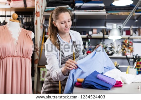Woman is choosing modern materials for new fashion collection in the workshop.