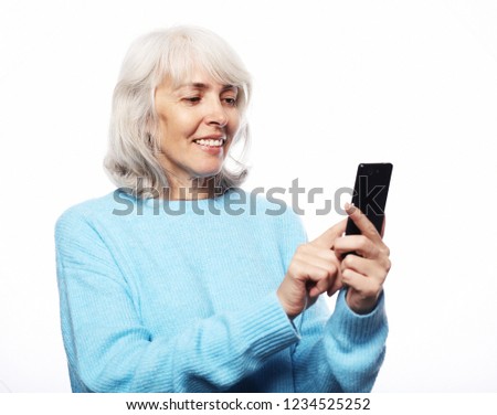 Lifestyle, technology and people concept: senior woman with smartphone texting isolated on white background