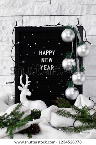 Happy new year words on a black board, a garland of Christmas balls, fir branches with cones on a white background, greeting card