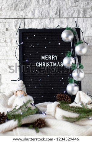 Merry Christmas text message made with white letters on a black wooden desk with knitted sweaters and cute winter doll on white background