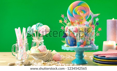 Mermaid theme candyland cake with colorful glitter tails, shells and sea creatures toppers for children's, teen's, novelty birthday and party celebrations, green background.