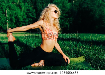 Picture of young curly-haired sports woman practicing yoga on ru