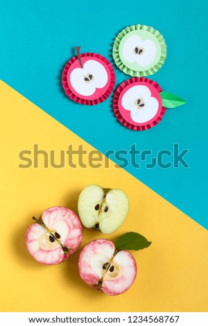 Apples cut in half and their paper models on two-color background. Paper handicraft and paper art