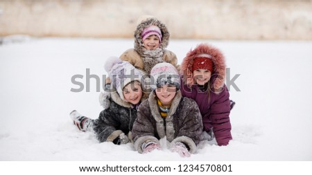 Funny children playing and laughing on snowy winter park, happy sisters