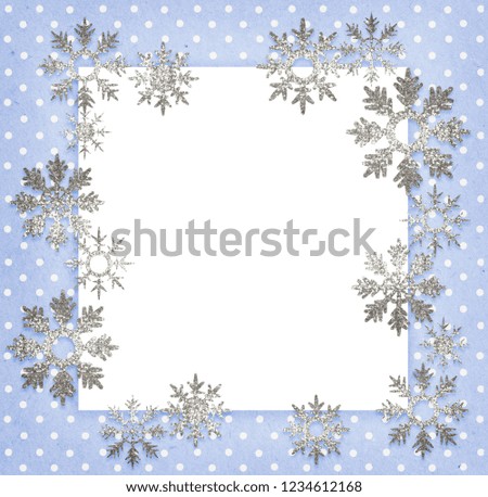 Blue polka dot background with white card and glitter snowflakes for Christmas