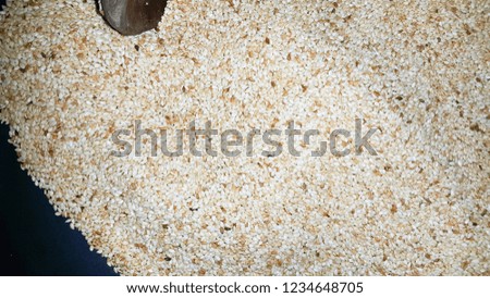 Toasted sesame seeds in a frying pan with wooden spoon
