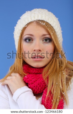 Young beautiful woman with snow on blue background